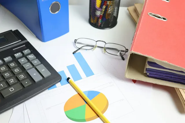 Mesa de trabalho com calculadora, gráficos financeiros e documentos